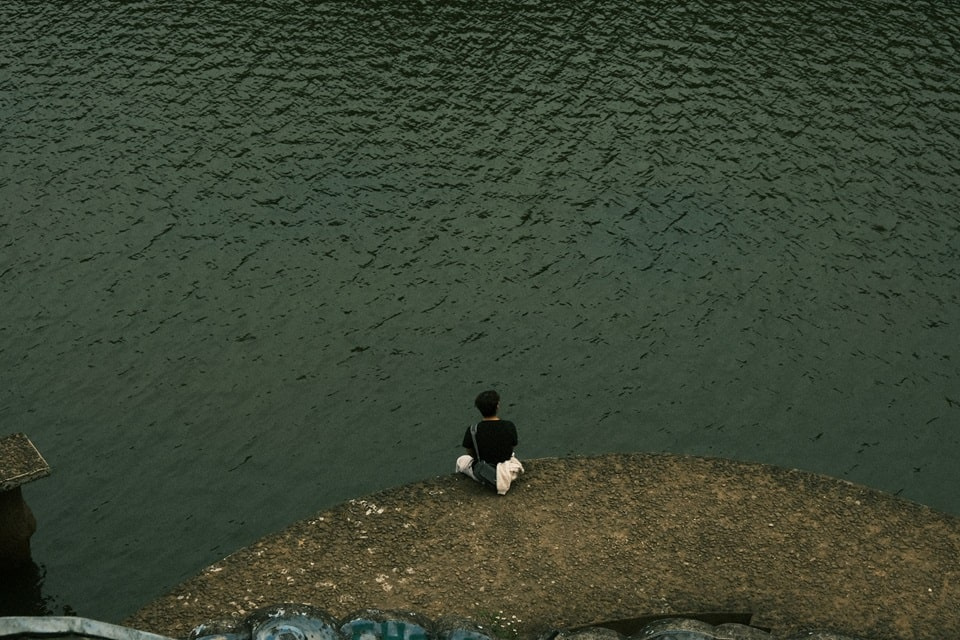 Feature image a person sitting on a rock near water, Difficult Times