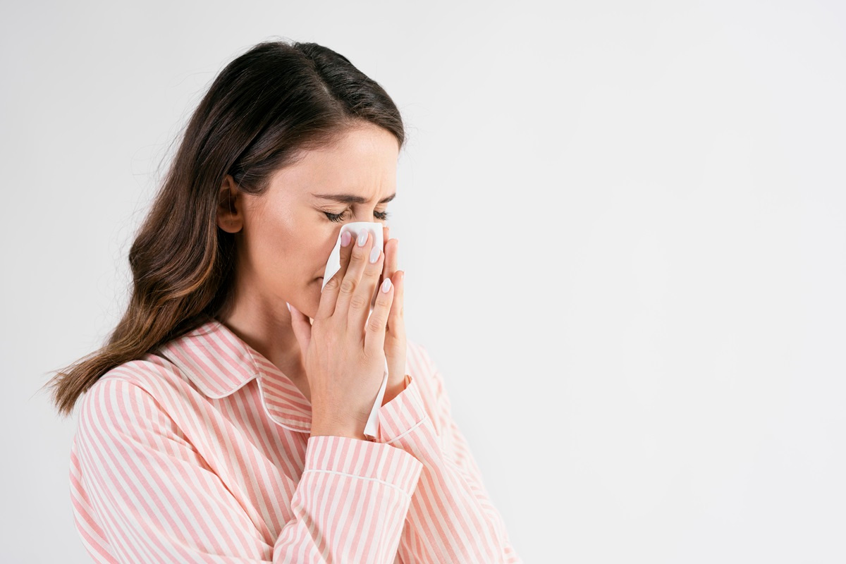 Feature image Young woman blowing her nose in studio shot